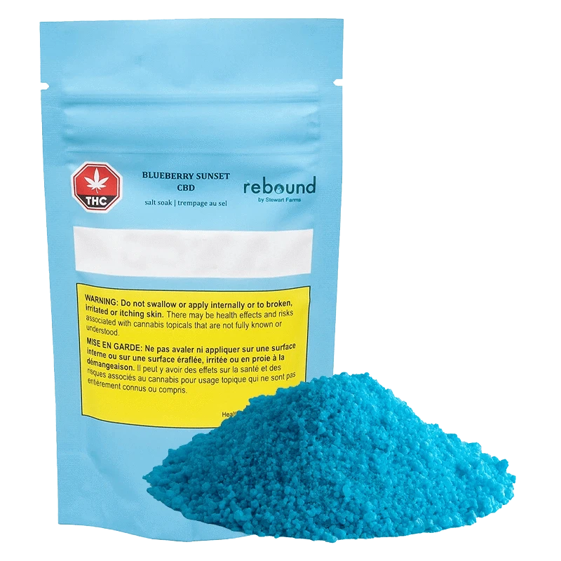 Front-facing pouch labeled Blueberry Sunset CBD Rebound with a bright mound of blue bath salts in front on a plain background
