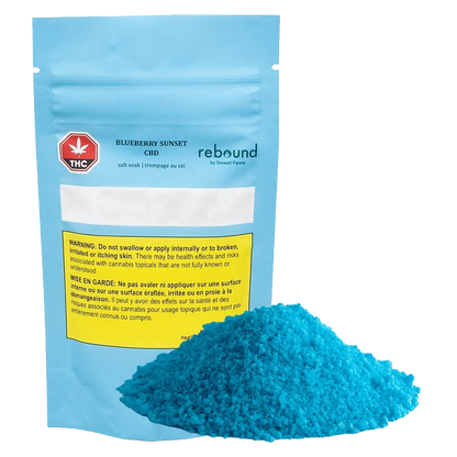 Front-facing pouch labeled Blueberry Sunset CBD Rebound with a bright mound of blue bath salts in front on a plain background