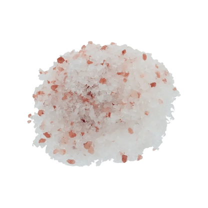 A close-up of the pink Frankinsence Dead Sea Himalayan Bath Salt crystals, scattered on a plain white surface.