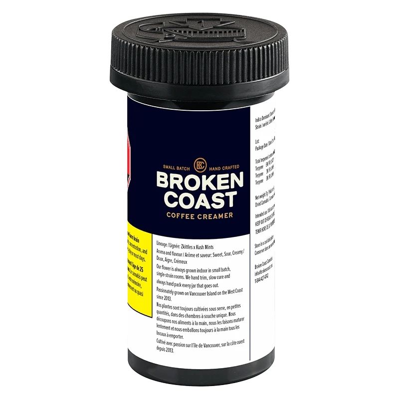 Three-quarter view of the Broken Coast Coffee Creamer black plastic jar with navy label, visible nutrition text and ribbed screw cap.