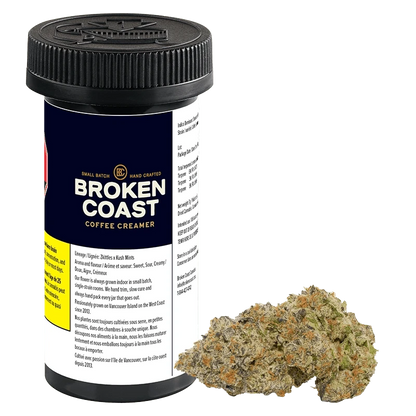 Front-three-quarter view of a black-lidded container and a cannabis bud, labeled Broken Coast Coffee Creamer, on a white background.