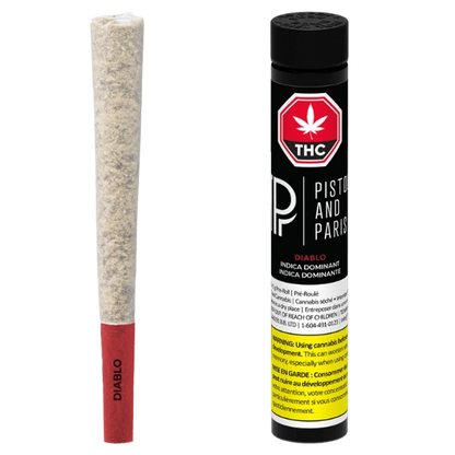 Studio-lit front view of a Diablo PR 1 x 1 g pre-roll with red paper tip beside its black Piston and Paris tube.