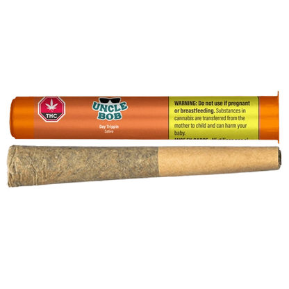 Horizontal studio shot of an orange Uncle Bob Day Trippin PR 1 x 0.5 g tube with a rolled joint placed below it on a white background