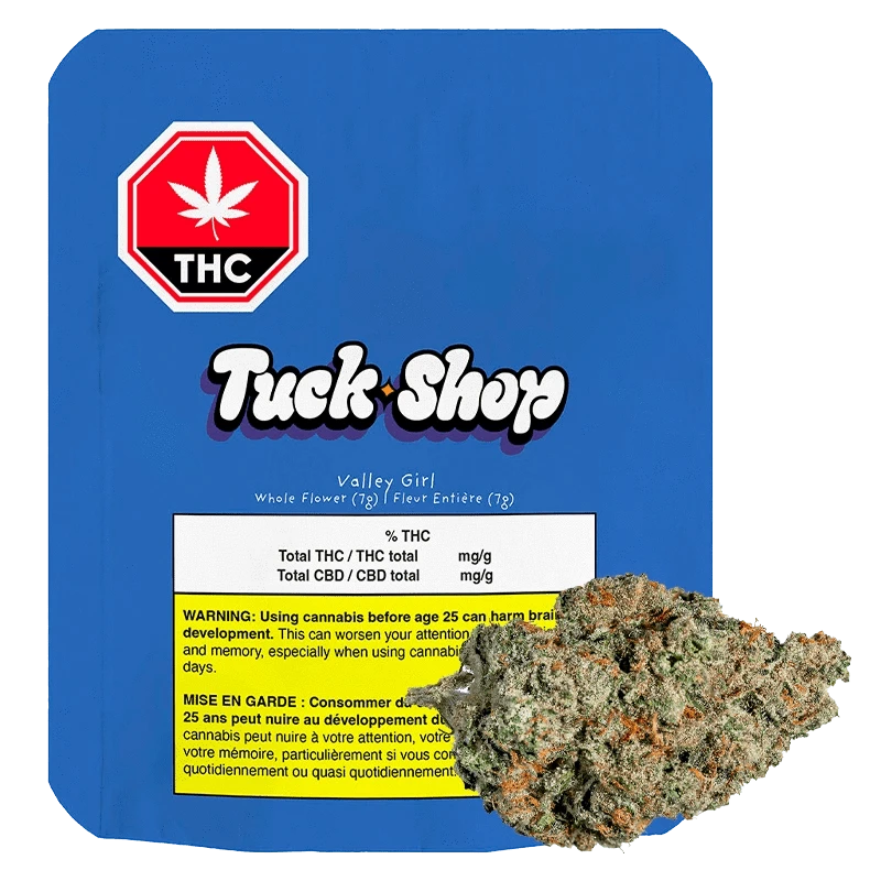 Front-facing shot of the Tuck Shop Valley Girl 7 g package on blue backing with a cannabis bud overlapping the lower right.