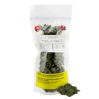 Front-facing photo of a clear resealable bag of Organic Electric Skunk showing dense green buds, a white product label and a yellow warning panel.