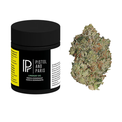 Three-quarter view of a black Pistol and Paris Lindsay OG jar with label details visible beside a frosty green bud on a white background