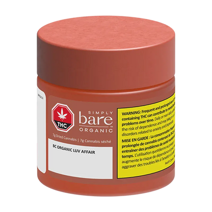 Front three-quarter view of a small red jar labeled "BC Organic Luv Affair" from Simply Bare Organic with a yellow warning panel.