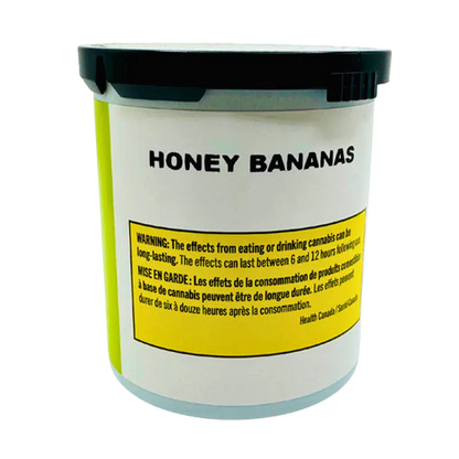 Front-facing view of a white container labeled Honey Bananas with a black lid and a yellow warning panel near the base