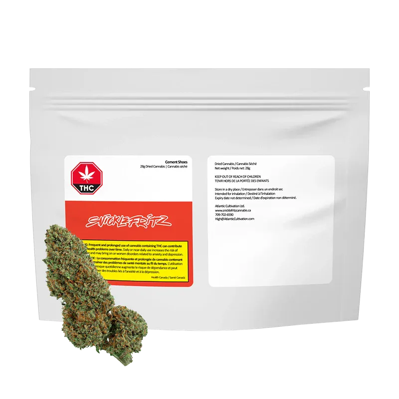 Front-facing, studio-lit image of a white resealable pouch labeled "Cement Shoes" by Snicklefritz with two green cannabis buds placed at the lower left.