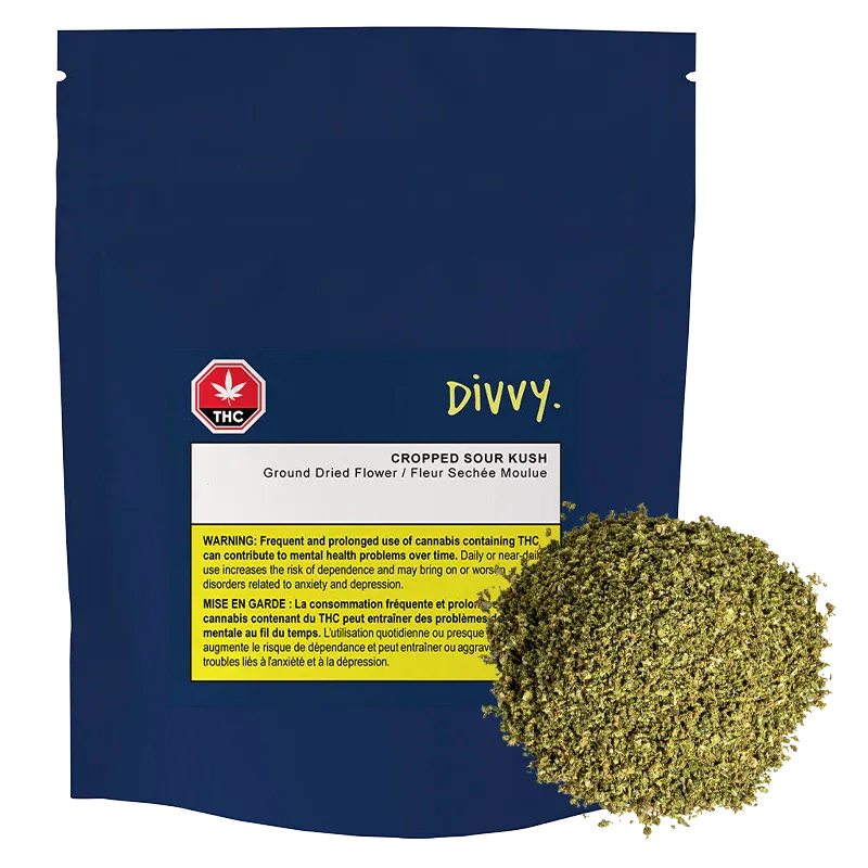 Front-facing navy pouch labeled "Divvy. Cropped Sour Kush" with a white and yellow warning panel and a loose 7 g mound of green dried flower at the lower right