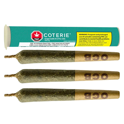 Horizontal flat-lay of three rolled joints with twisted tips and brown "OGB" filter ends below a teal Coterie Grape Gotti PR 3 x 0.5 g tube showing a yellow warning label.