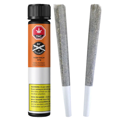 Vertical product shot of Tiger Balm PR 2 x 1 g showing the orange-and-white cylindrical tube with warning label beside two pre-rolled joints.