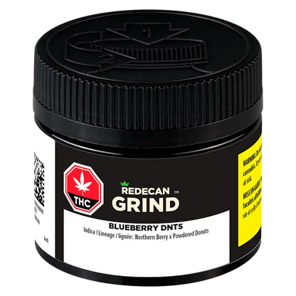 Close-up front view of a black jar labeled "Blueberry DNTs Grind" by Redecan Grind, showing textured screw-top lid and warning labels.