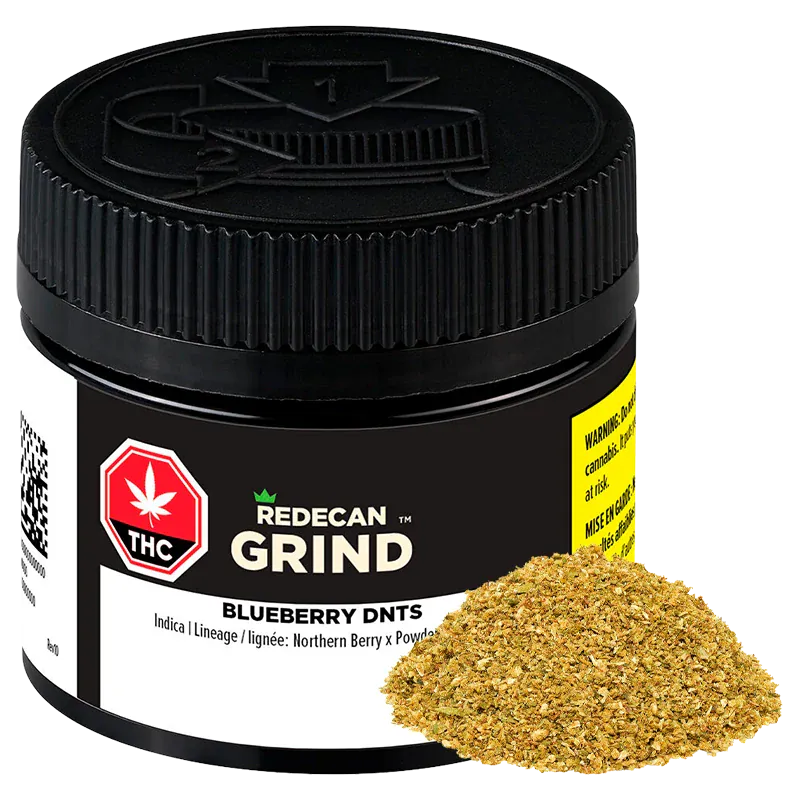 Close-up, three-quarter view of a black jar labeled "Redecan Grind Blueberry DNTs" with a pile of golden-green ground herb at its base.