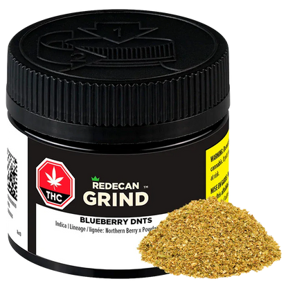 Close-up, three-quarter view of a black jar labeled "Redecan Grind Blueberry DNTs" with a pile of golden-green ground herb at its base.