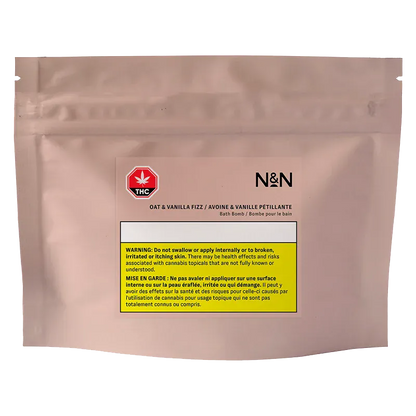 Front-facing shot of the blush pouch labeled N&N Oat & Vanilla Fizz Bath Bomb with a THC symbol and yellow warning block centered on the front.