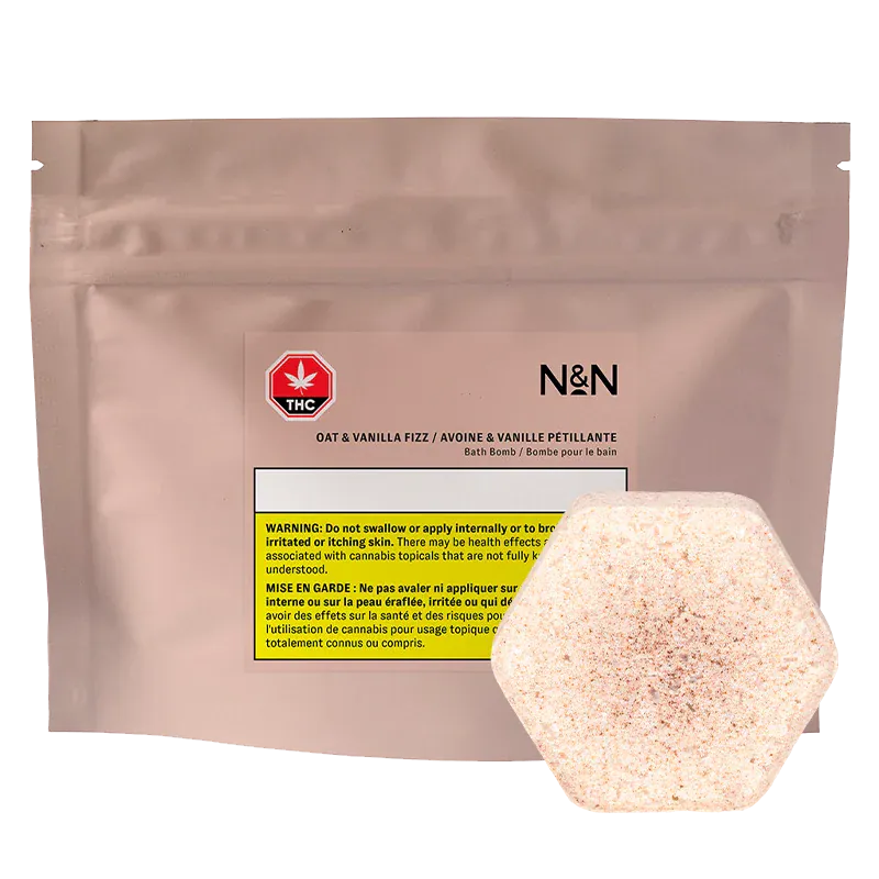 Front view of the N&N Oat & Vanilla Fizz Bath Bomb pouch in matte blush packaging with a hexagonal speckled bath bomb in front.