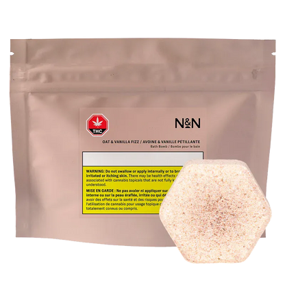Front view of the N&N Oat & Vanilla Fizz Bath Bomb pouch in matte blush packaging with a hexagonal speckled bath bomb in front.