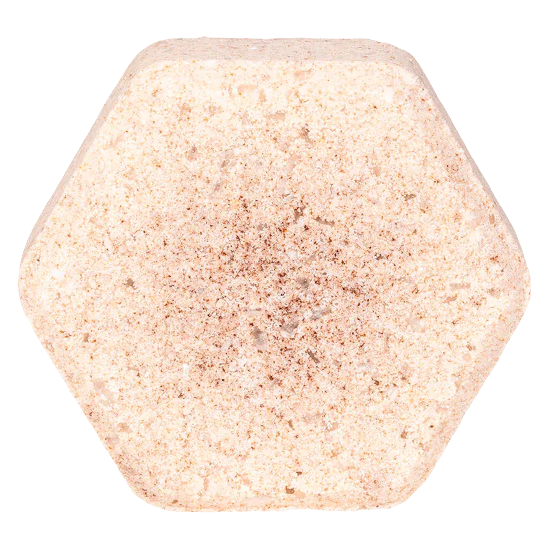 Top-down close-up of a hexagonal Oat & Vanilla Fizz Bath Bomb with a pale peach, speckled texture against a white background