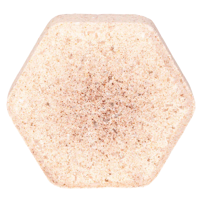 Top-down close-up of a hexagonal Oat & Vanilla Fizz Bath Bomb with a pale peach, speckled texture against a white background