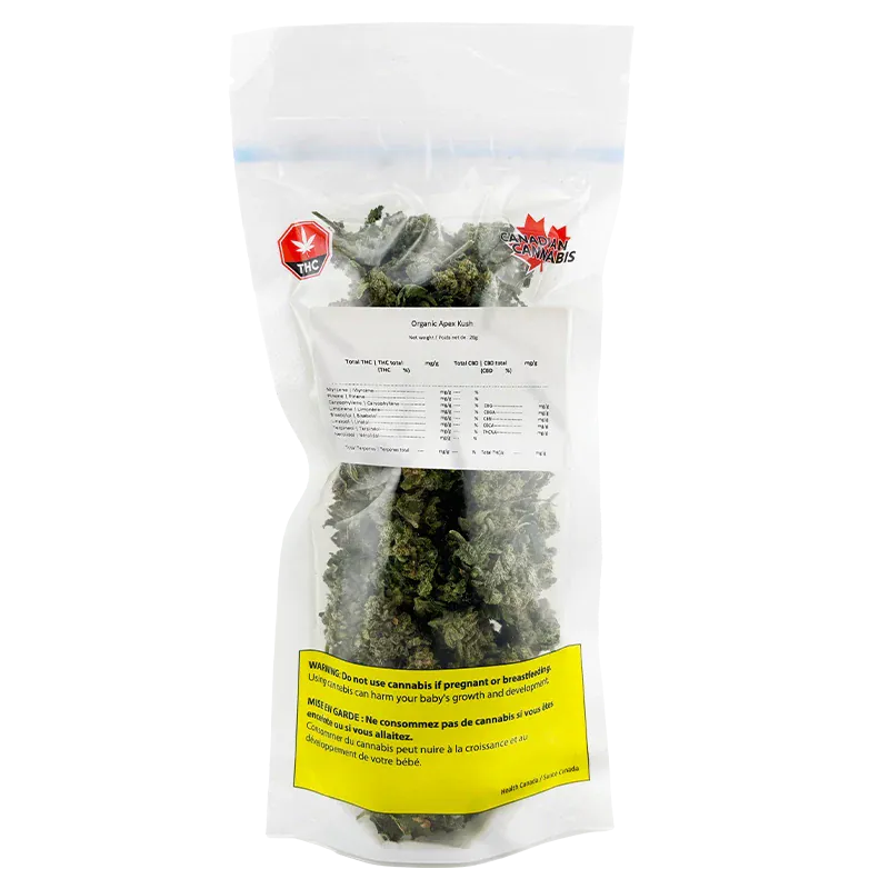 Clear front-facing view of a sealed bag of Organic Apex Kush showing dense green buds, a white label of contents, and a yellow warning panel.
