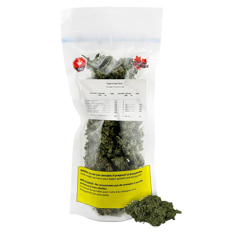 Front-facing shot of a clear resealable bag of Organic Apex Kush showing green buds inside, label text and a yellow warning panel.