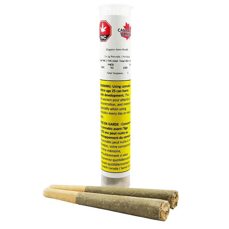 Tall front view of the Organic Apex Kush PR 2 x 1 g clear plastic tube with a yellow warning label, shown standing behind three pre-rolled joints.