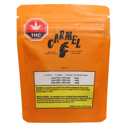 Front-facing shot of the orange Carmel Envy pouch with a black logo, THC symbol sticker, and warning panel visible.