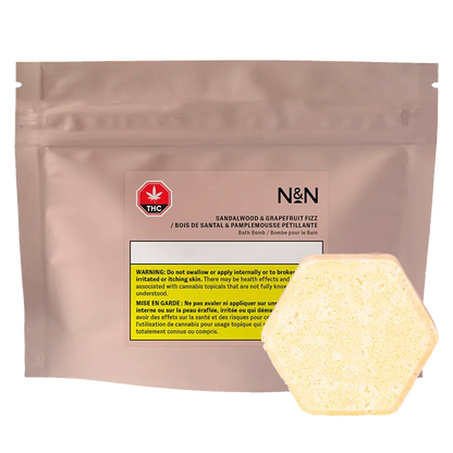 Front-facing pouch labeled N&N Sandalwood & Grapefruit Fizz Bath Bomb with a pale yellow hexagonal bath bomb resting at the lower right.