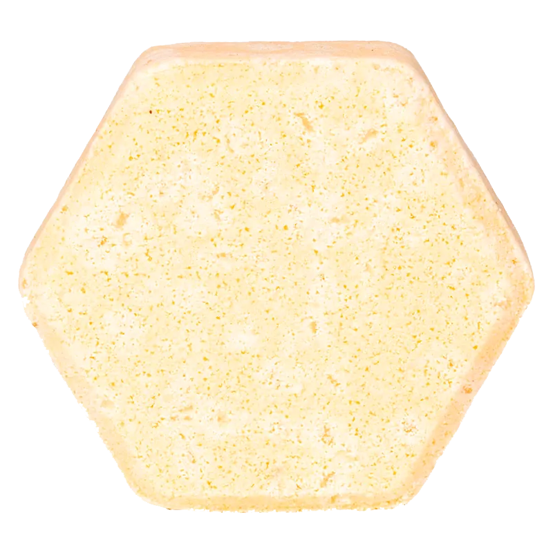 Top-down view of a pale yellow hexagonal Sandalwood & Grapefruit Fizz Bath Bomb against a white background.