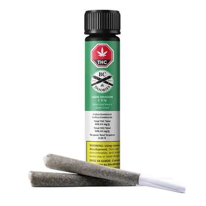 Front view of the Jade Dragon PR 2 x 1 g green tube standing upright with two pre-rolled joints lying diagonally in front.