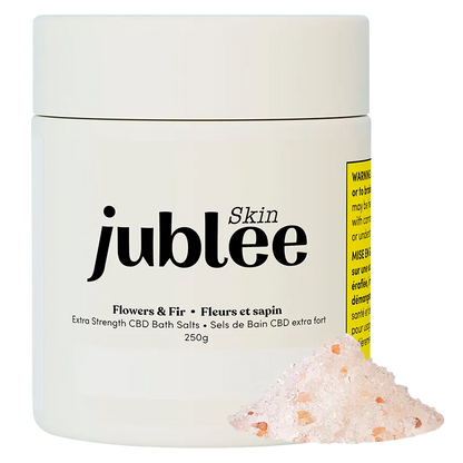 Front-facing jar of Jubilee Skin Flowers & Fir Extra Strength CBD Bath Salts with a small pile of pink bath salt in the foreground.