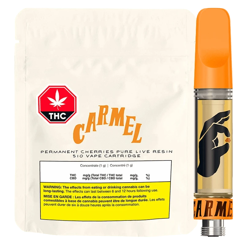 Front-lit product shot of the Permanent Cherreis Pure Live Resin Vape Cartridge showing a cream pouch labeled "CARMEL" beside a clear cartridge with an orange mouthpiece and black hand graphic.
