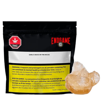 Close-up of the “Garlic Sauce on the Rocks Diamonds and Terp Sauce” packaging with a warning label and THC symbol against a dark backdrop.