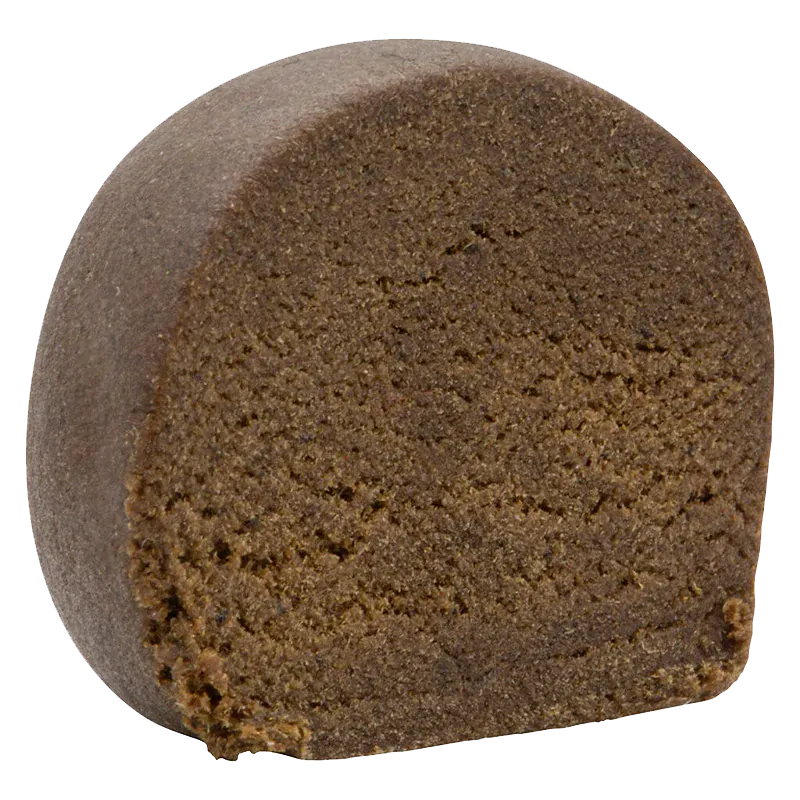 Close-up front view of a dense, dark brown half-cylinder of Montreal-Style Aged Hash showing its crumbly, textured interior.