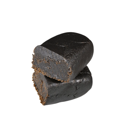 Close-up of a dark, blocky piece of Afghan Hash, angled against a plain white background.