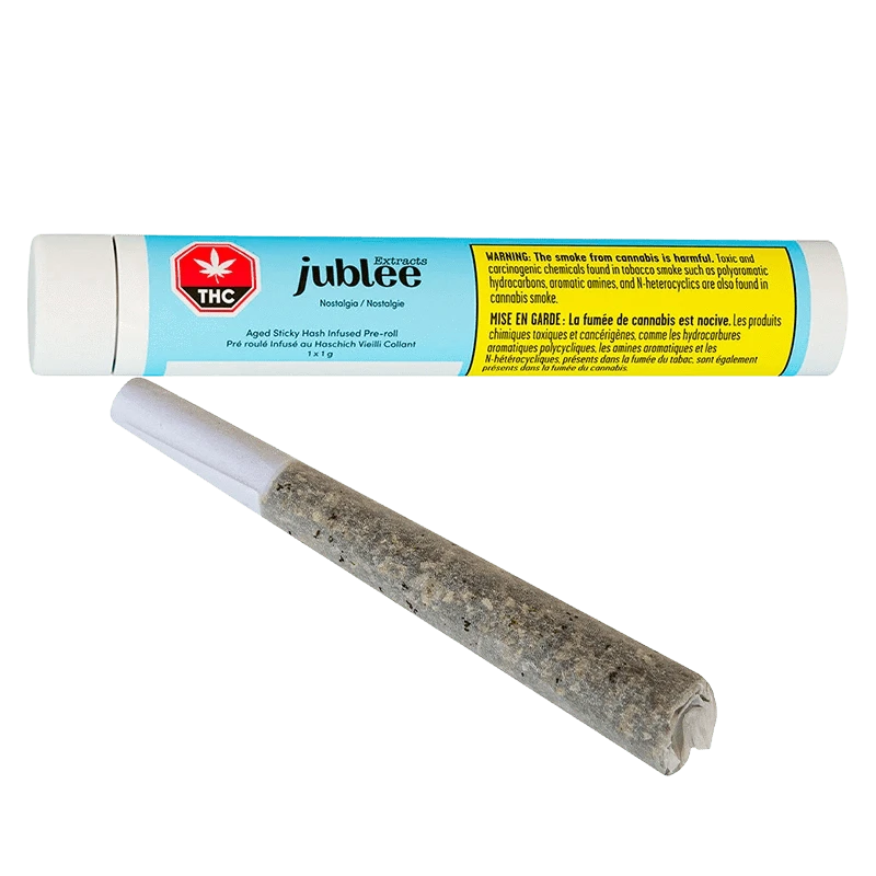 Close-up of a rolled joint in front of a horizontal blue and yellow tube labeled "Nostalgia - Aged Sticky Hash Infused PR 1 x 1 g" by jublee.