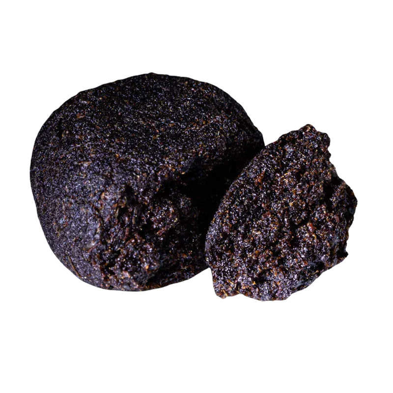 Close-up front view of a dark, crumbly ball and a halved piece of Bubble Yum Hash showing its granular, glistening texture.