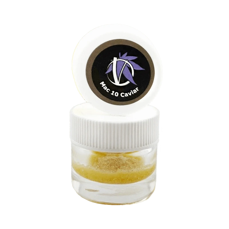 Close-up front view of a small clear jar with a white ribbed lid and opened cap showing a circular black logo reading "Mac 10 Caviar" above golden crumble inside, Mac 10 Caviar