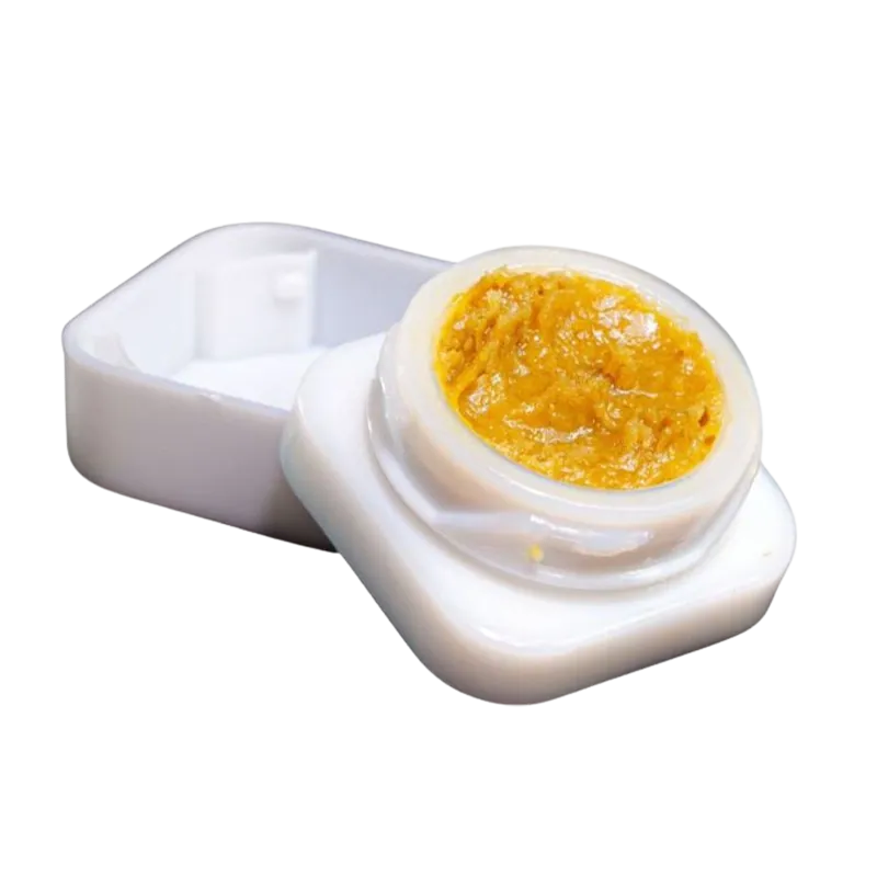 Close-up overhead view of a small white container holding golden resin, labeled Goldie Knox Jar Live Rosin.