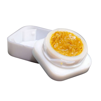 Close-up overhead view of a small white container holding golden resin, labeled Goldie Knox Jar Live Rosin.