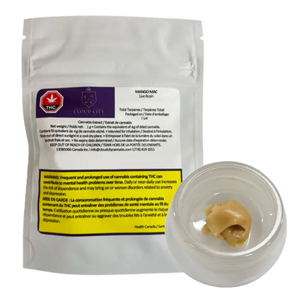 A white resealable pouch and a small clear jar photographed from a slight overhead angle showing the tan cannabis concentrate next to the pouch labeled Mango Mac Live Rosin.