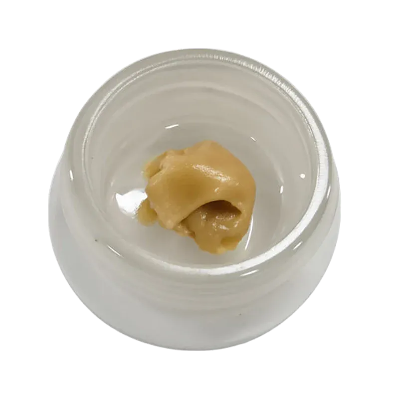 Top-down view of a pale gold dab of Mango Mac Live Rosin resting in the center of a small white glass jar.