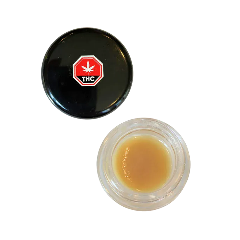 Top-down view of an open jar of Strawberry OG Whipped Live Resin showing light amber concentrate beside its black lid with a red THC symbol.