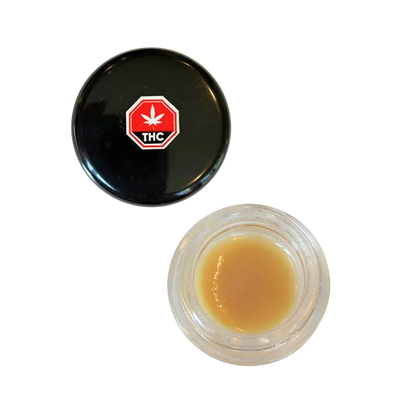 Top-down view of an open jar of Strawberry OG Whipped Live Resin showing light amber concentrate beside its black lid with a red THC symbol.