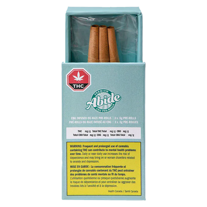 Front view of a teal box labeled "CBG Infused OG Haze PR 3 x 0.5 g" with three brown pre-rolls visible in an open top and a warning label on the front