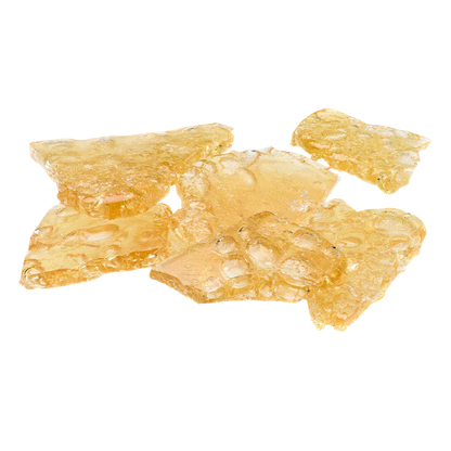 Close-up of amber, translucent shards of Peanut Butter Breath Shatter arranged on a white background.