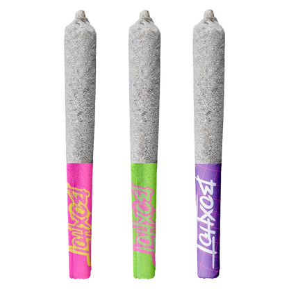 Three-quarter front view of three Diamond Doobies Deluxe Trifecta Infused PR 3 x 0.5 g pre-rolls standing upright, each with a grey ash-coated cone and bright pink, green, and purple branded paper tips.