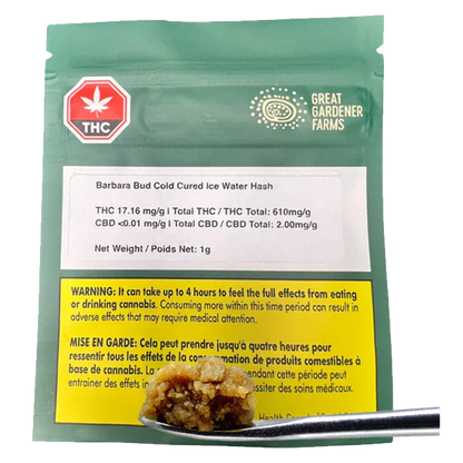 Close-up of a metal scoop holding a golden nugget of concentrate in front of a green pouch labeled Barbara Bud Cold Cured Ice Water Hash.