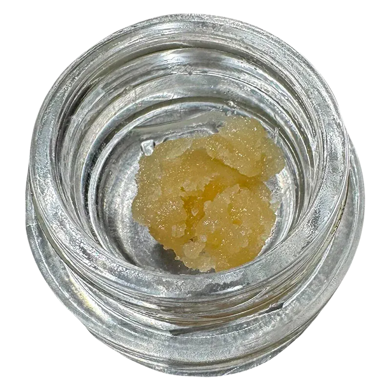 Top-down view of a pale yellow sugar-like concentrate in a small clear jar labeled Turbo Sugar Wax.